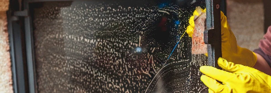 Person reinigt Kaminofenscheibe